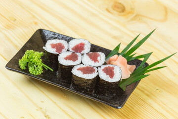 Sushi maki with Tuna in a white plate placed on a wooden floor