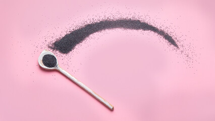 Composition with poppy seeds on pink background.