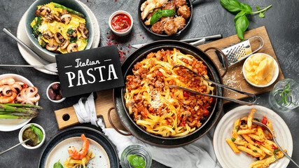 Assortment of Italian pasta with traditional sauces for dinner on dark background. Homemade food concept