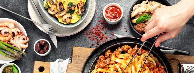 Assortment of Italian pasta with traditional sauces for dinner on dark background. Homemade food concept