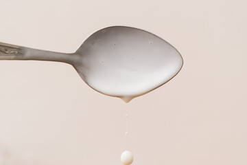 Fresh yogurt on a spoon isolated on white. Delicious yogurt drips from the spoon. Liquid drops....