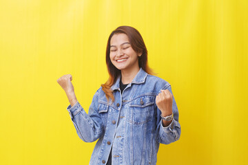 asian woman standing closed eyes smiling happily clenching fist with successful gesture