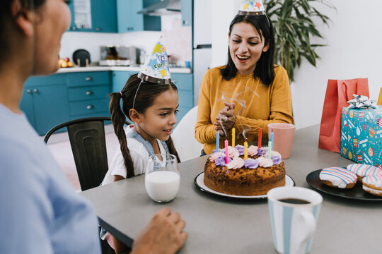 Latinx LGBTQ women mother family with daughter child celebrating a happy birthday at home in Latin America