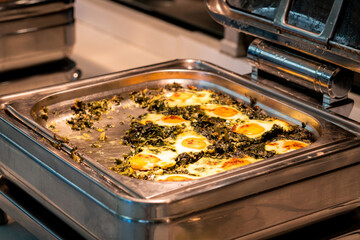 All-inclusive buffet food in heating trays in hotel restaurant with eggs with spinach for breakfast