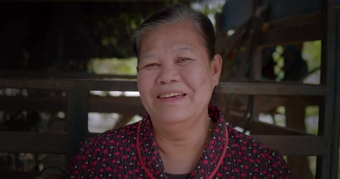 Slow motion scene of happy smiling Asian female farmer who is an elderly person live in rural area, standing in front of her agricultural truck.