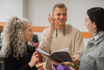 Two girls and a guy are talking in sign language. Three deaf students chatting in a university classroom.