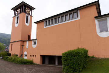Orange catholic church with clock tower at Village of Stein, Canton Aargau, on a cloudy spring day. Photo taken May 6th, 2022, Stein, Switzerland.