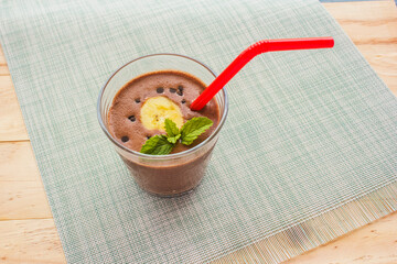 Chocolate Banana Shake Topping Sprinkled with Chocolate Chips, Banana and Mint Leaves with Straw on Cloth