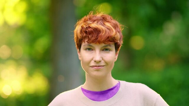 Smiling non-binary person looking at the camera outdoors