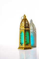 Golden lantern with shadow from sun light on white background.