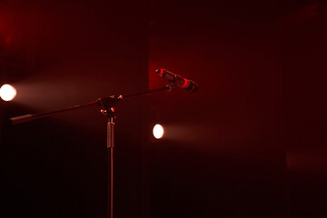 Professional stage microphone in a bright red spotlight on a dark background. High quality photo