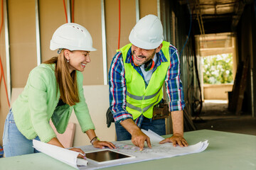Woman architect and men contractor examining plans on construction site.