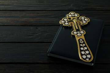 Cross on Bible on wooden background, space for text