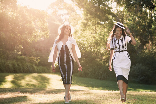 Two girls in dresses walking in the park backlit by sun