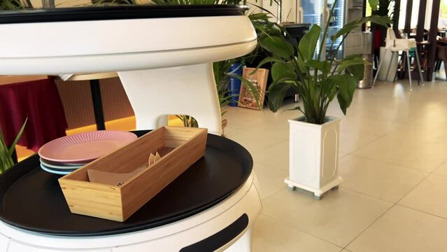 A serving robot in a cafe that carries spoons and plates
