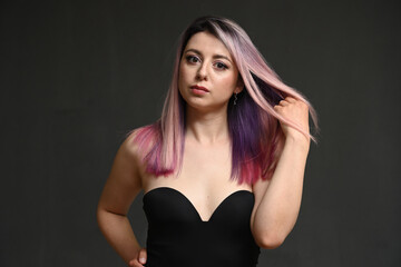 Portrait of a caucasian serious girl with dyed hair on a gray background