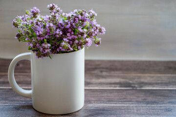 Fresh thyme flowers in a white cup. Fresh organic thyme flowers. Flowers of thyme creeping. Thyme. Phytotherapy. Selective focus.