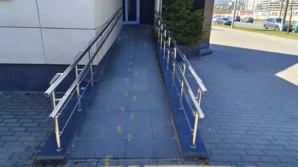 A ramp with metal railings is installed to enter a municipal building for people with disabilities...