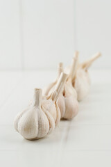 Closeup of Garlic Bulbs on White Table with Other Garlics on Background.