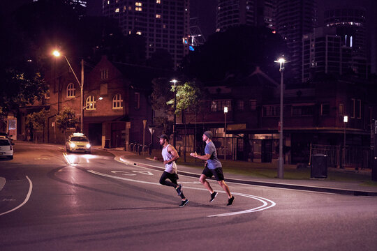 Two men fitness training in urban city at night running