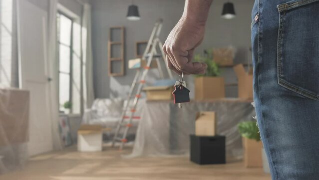 Buying renting new house concept,back view of man's hand holding home key close up,moving into new apartment