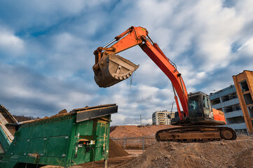 Excavator loads soil in mobile crushing and sorting complex