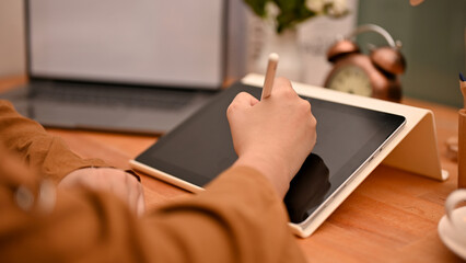 Female graphic designer or freelancer using digital tablet touchpad. cropped image