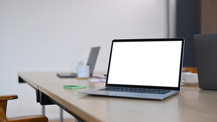 Fototapeta premium Laptop computer, coffee cup and documents at modern conference room. Blank screen for your advertise text