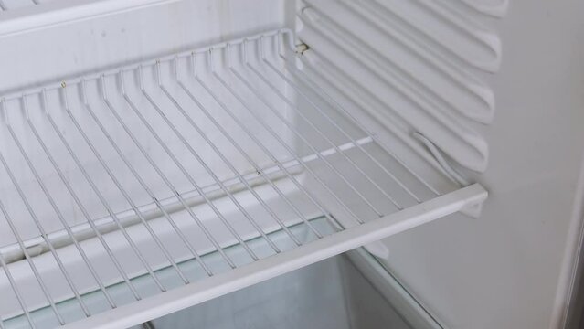 The man's hand opens an empty refrigerator with the word crisis on it and takes one single banana. Conceptual 4k raw video. Idea of ​​economic crisis, food shortage, poverty.