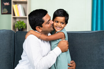 Obraz premium little toddler daughter hugging father by kissing at home - concept of love, parenthood and harmony