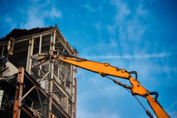 Fototapeta na wymiar Hydraulic cutter on crane rig destroys industrial building