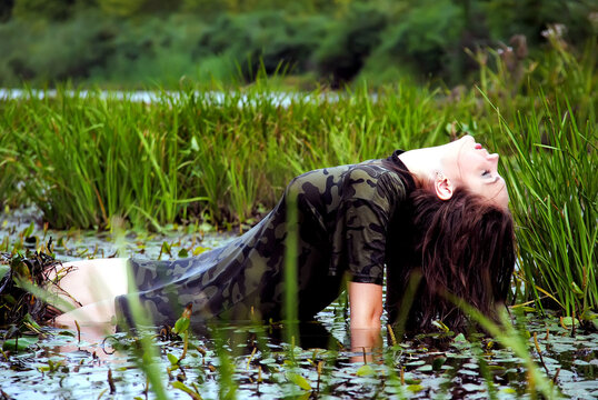 wet beautiful young girl in military uniform in the Ukrainian swamp, a lot of splashes