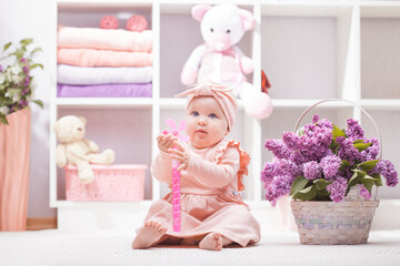 Fototapeta na wymiar baby with lilac flowers at home or kindergarten