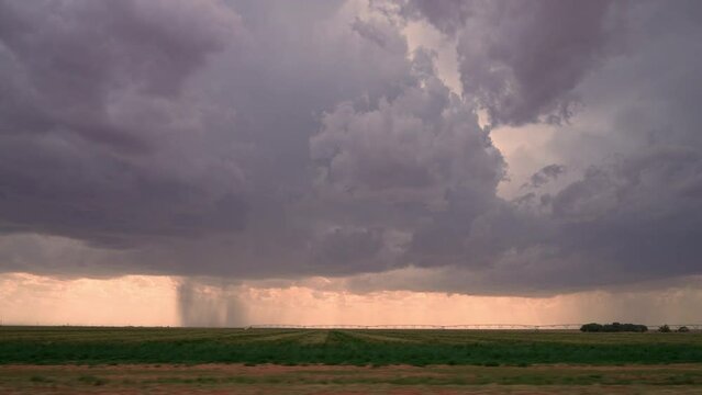 View from vehicle driving down road looking at rainstorm in the distance while storm chasing in Texas.