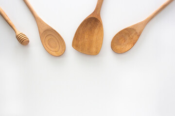 Wooden kitchen tools, spoon, honey dipper and spatula, top view shot on white background.