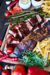 Barbecue pork ribs on wooden serving board on picnic table outdoors