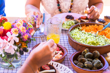 Group of hands sharing food and drink. Caucasian peoples enjoying brunch or meal together. Fruits and vegetables on the wooden table. Sunlight outdoor on the terrace