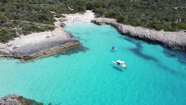 Aerial view with dron of a beautiful beach in Menorca, Spain. Boat floating in transparent and turquoise water in the Balearic Islands