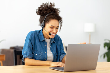 Successful African American woman in headset, office employee or call center worker sitting in a...