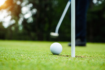 Golf ball and golf club in beautiful golf course at sunset background.