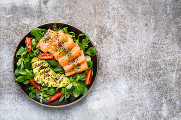Salmon fish fillet with fresh salad, avocado top view.