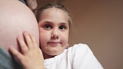 pregnant woman close-up belly. a daughter little girl hugs her mother belly. happy family baby pregnancy newborn concept. baby listening to pregnant mother belly. happy family expecting newborn