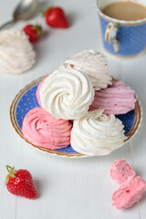 Natural multicolored marshmallows marshmallows on a saucer and a cup of coffee or tea with milk. Close-up