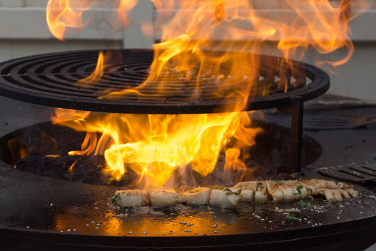 The process of cooking seafood: sea scallop and squid. Open fire. Close-up.
