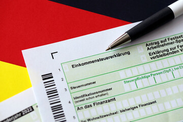 German annual income tax return declaration form with pen on flag close up. The concept of tax...