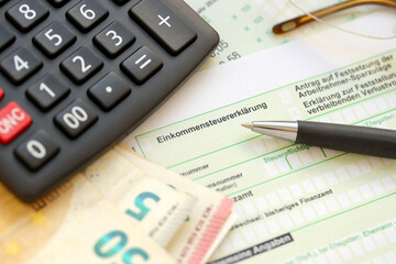 German income tax return form with pen and european euro money bills lies on accountant table close...