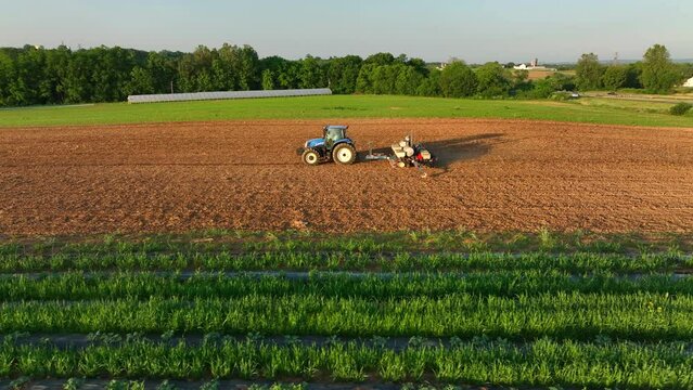 Aerial truck shot and orbit of New Holland tractor pulling seeder in rural Pennsylvania. American agriculture business theme. Beautiful lighting.
