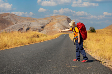 Young asian woman backpacks  as standing near road and hitchhiking. adventure travel, road trip...