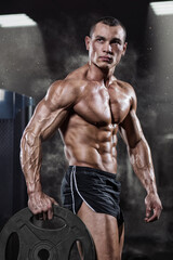 Fototapeta na wymiar Professional bodybuilder with weight disk in gym