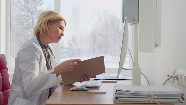 Female doctor working at computer reading patient's record